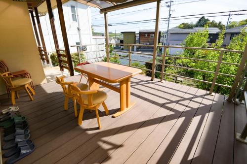 a wooden porch with a table and chairs on a balcony at 民泊 丘の上 in Seto
