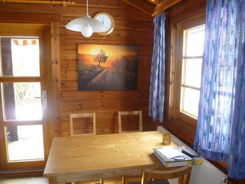 a dining room with a wooden table and two windows at Ferienhaus Lauter 57 in Hayingen