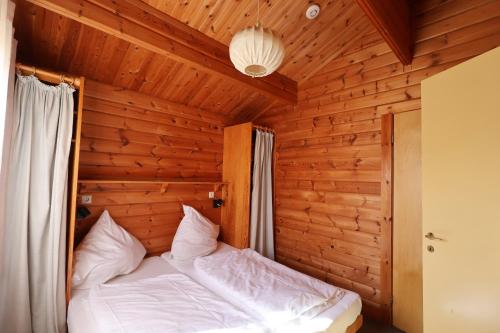 a bed in a room with a wooden wall at Ferienhaus Neckar 46 in Hayingen