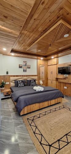 a large bed in a room with wooden ceilings at Saathi Stay & Cafe in Vashisht