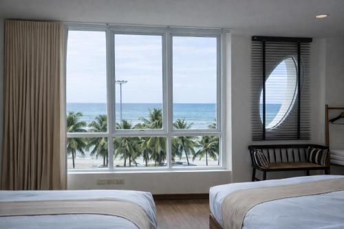 a bedroom with two beds and a large window with the ocean at The Beach Bangsaen by Thanthita next to Wonnapa beach FREE DISNEY PLUS in Bangsaen