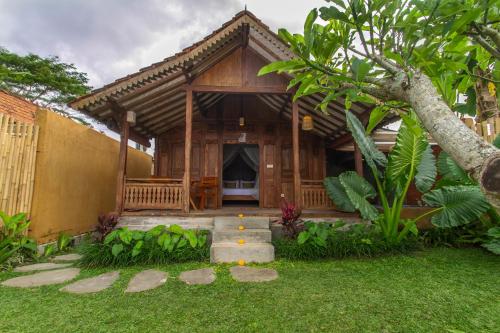 a wooden house with a porch in a garden at TUJUH Angel by GenuineHost in Ubud
