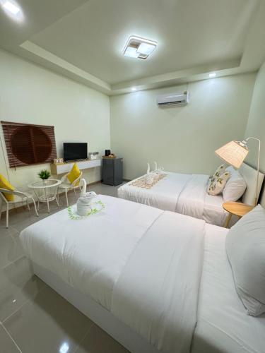 a room with two beds and a couch and a tv at Khaosok Embrace Resort in Khao Sok National Park