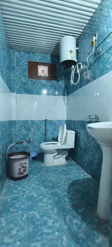 a blue bathroom with a toilet and a sink at Omji Niwas - Kalindi in Kharsālī