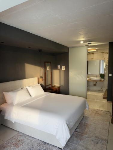 a bedroom with a large white bed and a bathroom at BASIC MANSION plus with swimming pool & free parking in Šibenik