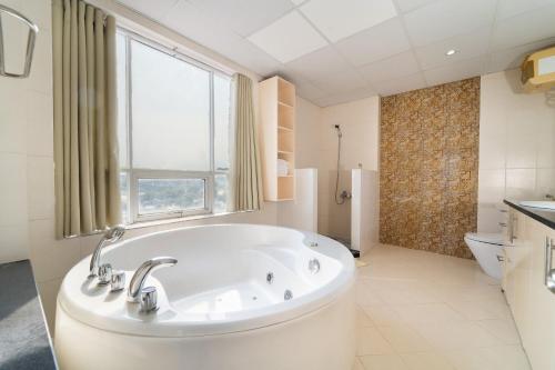 a white bathroom with a tub and a window at Palette Muine Boutique Hotel Near Mui Ne Beach in Mui Ne