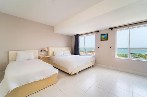 two beds in a room with a view of the ocean at Palette Muine Boutique Hotel Near Mui Ne Beach in Mui Ne