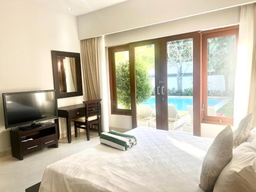 a bedroom with a bed and a television and a pool at Peninsula Villa in Nusa Dua