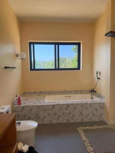 a bathroom with a bath tub and a window at Phangan Sky Villa in Ban Madua Wan