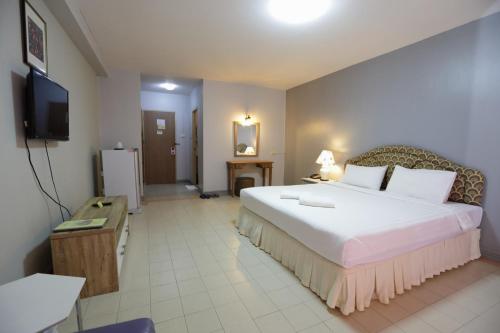 ein Hotelzimmer mit einem großen Bett und einem Fernseher in der Unterkunft โรงแรมพิณ in Lampang