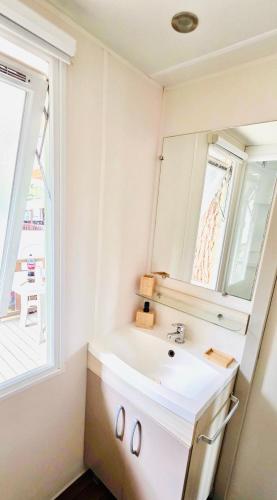 a bathroom with a sink and a mirror at Mobil home 3 chambres - Homair parc des 7 fonts 3 étoiles in Agde