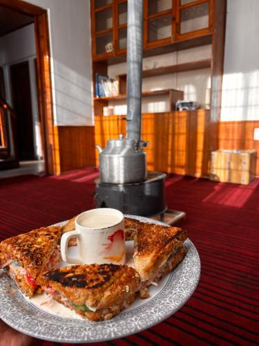 a plate with two slices of pizza and a cup of coffee at Mistvale Cottage in Manāli