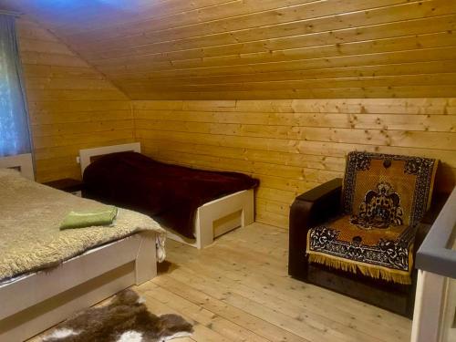 a room with a bed and a chair in a cabin at Дідова Хата in Shibeny