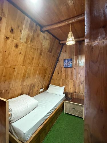 a bed in a room with a wooden wall at Chilux Manali in Manāli
