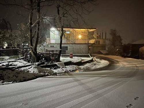a snow covered street with a house at night at Bir Breeze Homestays in Bīr