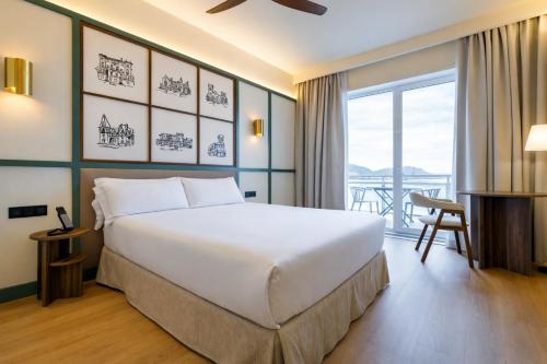 ein Schlafzimmer mit einem großen Bett und einem Balkon in der Unterkunft Petit Palace Tamarises in Getxo