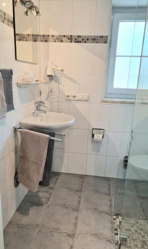 a white bathroom with a sink and a shower at Harlacher-Mühle in Stetten