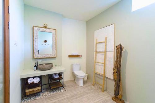 a bathroom with a toilet and a sink and a mirror at Dwayne 1 BR Standard Room in Kuta Lombok