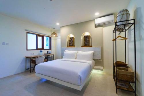 a bedroom with a white bed and a desk at Dwayne 1 BR Standard Room in Kuta Lombok