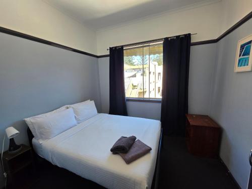 a bedroom with a white bed with a window at Coogee Beach House in Sydney