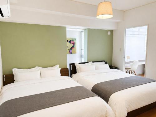 two beds in a room with green walls at Grand Reve KODEKI Near Nagoya Dome in Yadachō
