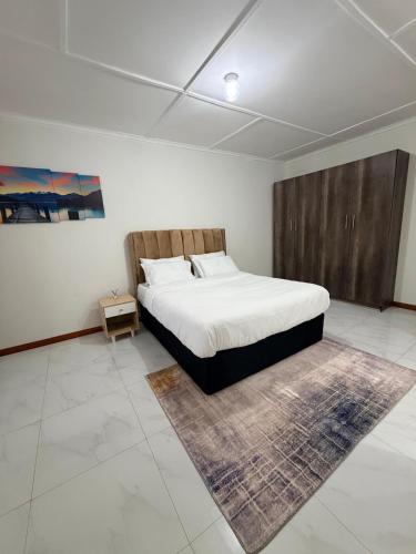a bedroom with a large bed and a rug at Destiny Executive Apartments in Solwezi