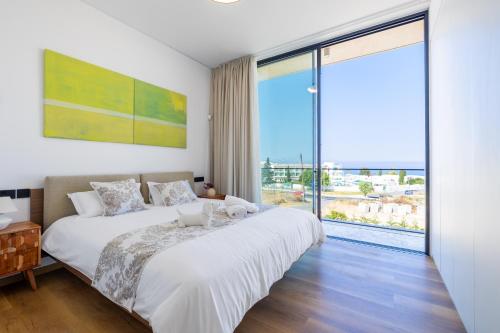a bedroom with a large bed and a large window at MITO Seaview by Serbellas in Kissonerga