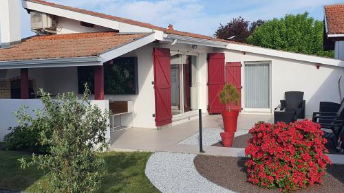 a small white house with red doors and flowers at La Parent'aise in Parentis-en-Born