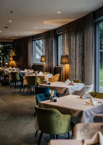 a dining room with tables and chairs and windows at Aktiv & Genusshotel Lodenwirt in Vandoies