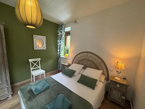 a bedroom with a bed with green walls and a chair at Gite Des 3 Chateaux in Ribeauvillé