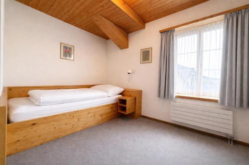 a small bedroom with a bed and a window at Golf Hotel Des Alpes in Samedan