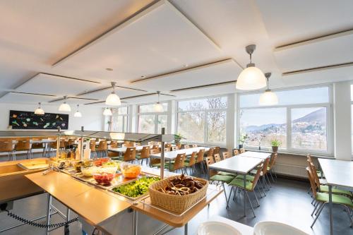 a dining room with tables and chairs and windows at Jugendherberge Bad Urach in Bad Urach