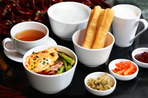 a table with bowls of food and cups of tea at JW Marriott Hotel Chongqing in Chongqing
