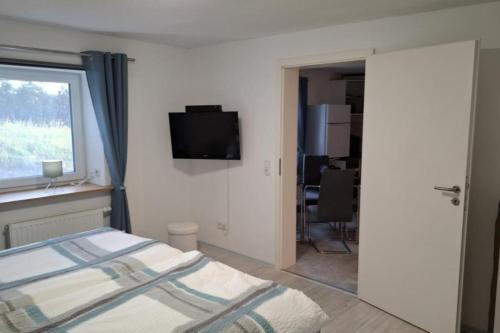 a bedroom with a bed and a television on the wall at NEU! Ferienwohnung am Ahlberg in Toppenstedt