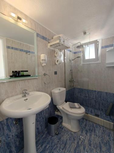 a bathroom with a sink and a toilet and a mirror at Kiklamino Sunset Suites in Oia