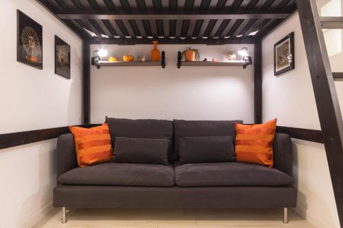 a black couch with orange pillows in a room at LittleAndCosy in Turin