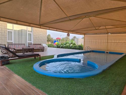 a swimming pool under an umbrella in a yard at Katara Garden in As Suwayq