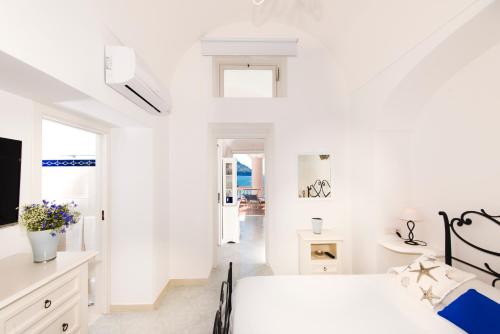 a white bedroom with a bed and a tv at Exclusive Apartments Positano in Positano