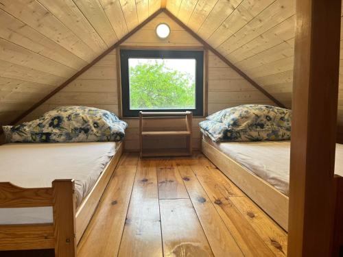 two beds in a small room with a window at Domek u Patryka in Mrągowo