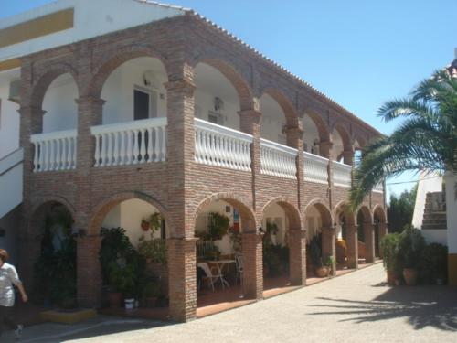 a large brick building with arches and a palm tree at Apartamentos Bolonia Paraiso in Bolonia