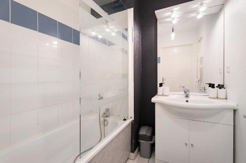 a white bathroom with a sink and a bath tub at Le Cocon De Laurence in Pleurtuit