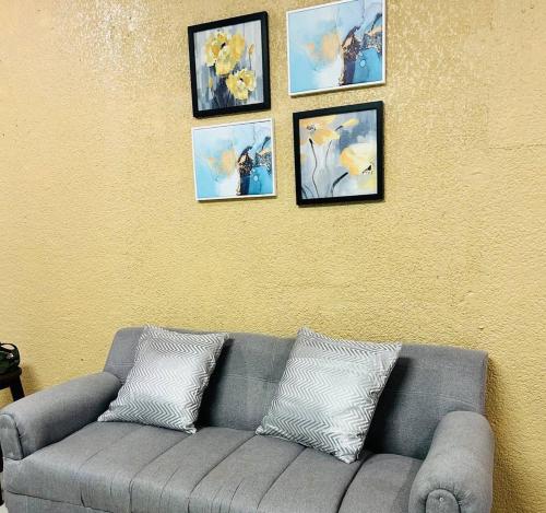 a gray couch against a yellow wall with pictures at Suite Antiguo in Antiguo Cuscatlán