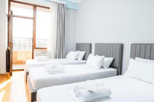 a room with three beds with white sheets at City View 2BR With Balcony, Steps To Cascade And North Avenue l New Building in Yerevan