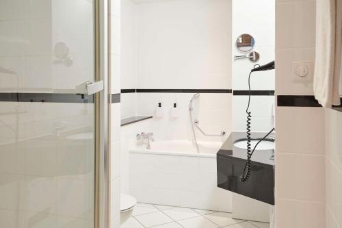a white bathroom with a shower and a sink at Scandic Wrocław in Wrocław