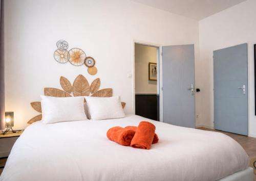 a white bed with an orange stuffed animal on it at Le Repaire des 12- Hypercentre, jardin, idéal groupe, 5 chambres 5 salles de bain in Saint-Omer