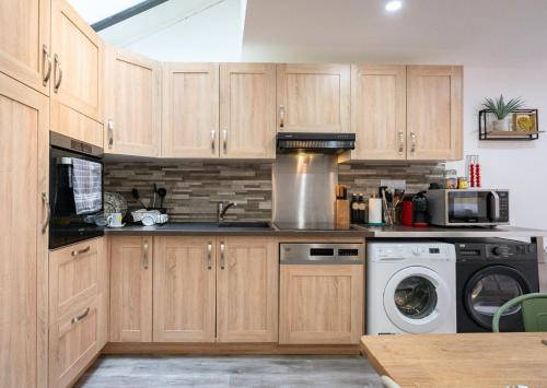 a kitchen with wooden cabinets and a washer and dryer at Le Repaire des 12- Hypercentre, jardin, idéal groupe, 5 chambres 5 salles de bain in Saint-Omer