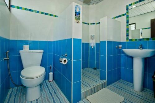 a blue and white bathroom with a toilet and a sink at Balay Tuko Garden Inn in Puerto Princesa City