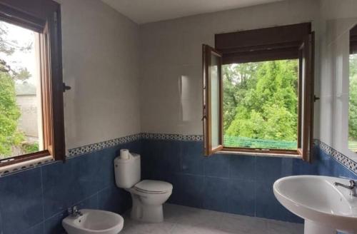 a bathroom with a toilet and two sinks and a window at Estación celorio in Celorio