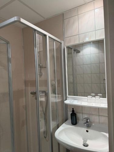 a white bathroom with a shower and a sink at HELENA Hotel & Restaurant in Mirow