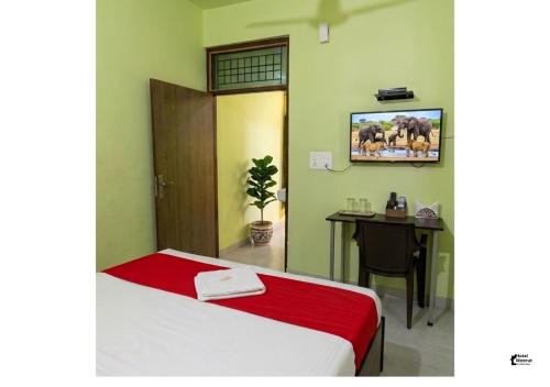a room with a bed and a desk with a tv on the wall at Hotel HMI International in Meerut